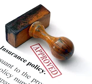 Close-up of an "APPROVED" rubber stamp on an insurance policy document